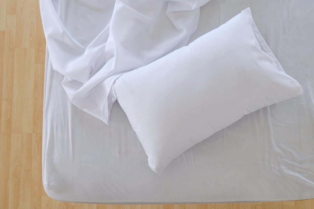 Almohada blanca y colchón con sábanas blancas