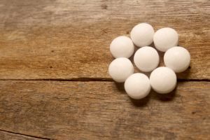 Bolas de naftalina blancas sobre fondo de madera.