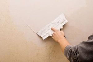 Un hombre está sellando las grietas de la pared