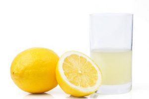 Un limón en rodajas con un limón entero y zumo