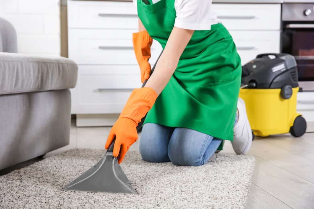 Una mujer está limpiando la alfombra
