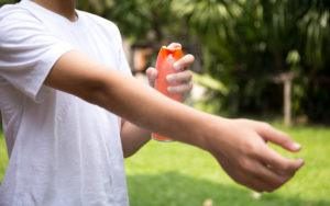 Un hombre está ahorrando repelente de insectos en su brazo