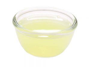 El primer plano del tazón del jugo de limón sobre el fondo blanco