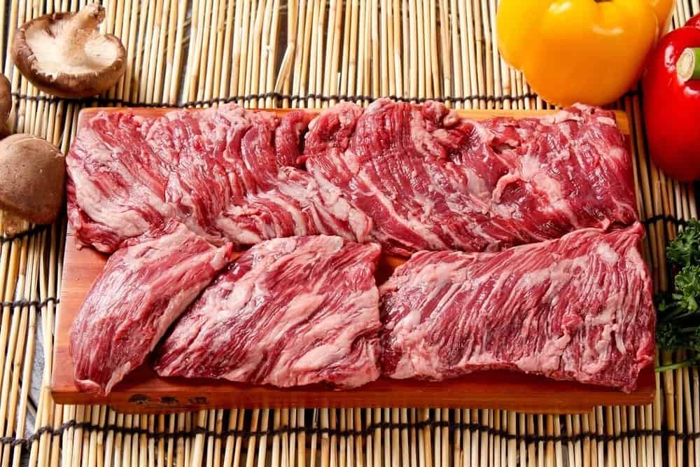 Carne cruda en la mesa de madera con algunas verduras