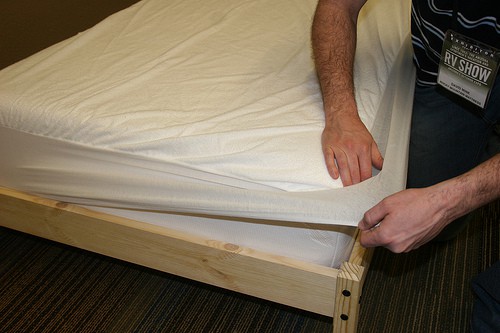Hombre es cubriendo su cama con la cama protectores de la cama