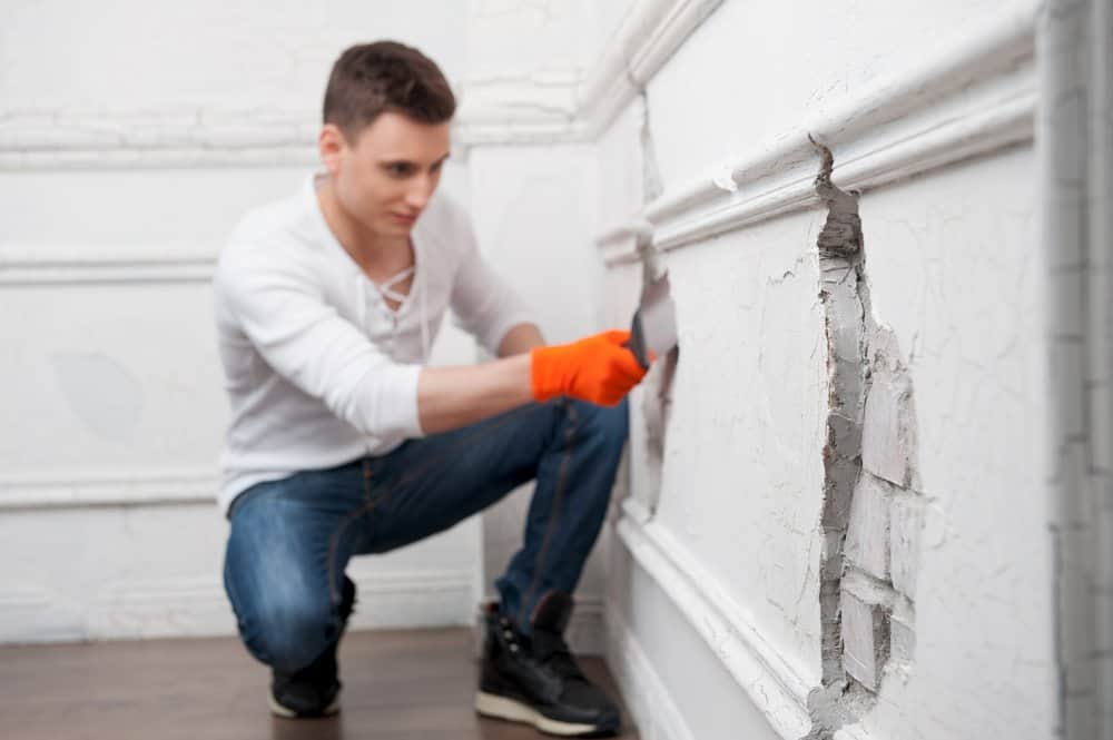 Un hombre apuesto está sellando grietas de la pared