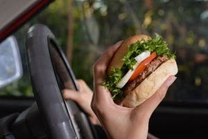 Comer hamburguesa en coche mientras conduce