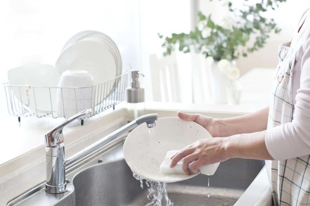 Una mujer está lavando platos en casa