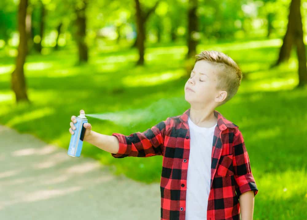 Un lindo está usando insectos spray en su cara