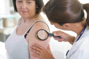 Mujer que ve médico para el control dermatológico.