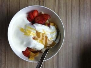 Yogur de mantequilla de fresa con cuchara en la mesa de madera